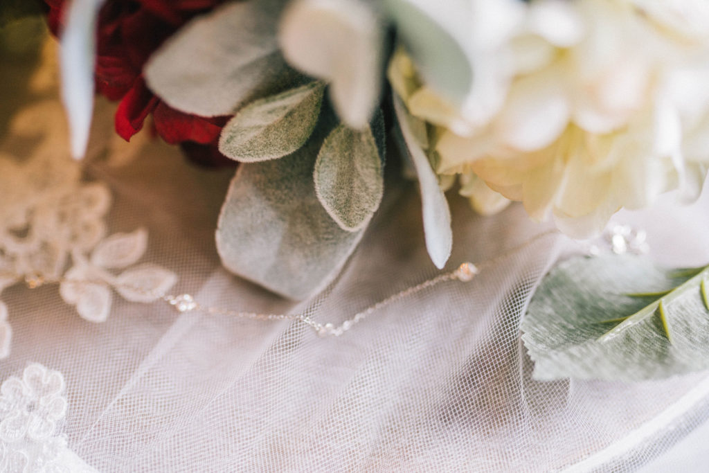 detail shot of bride cream, burgundy and eucalyptus bouquet sitting on top of her veil.