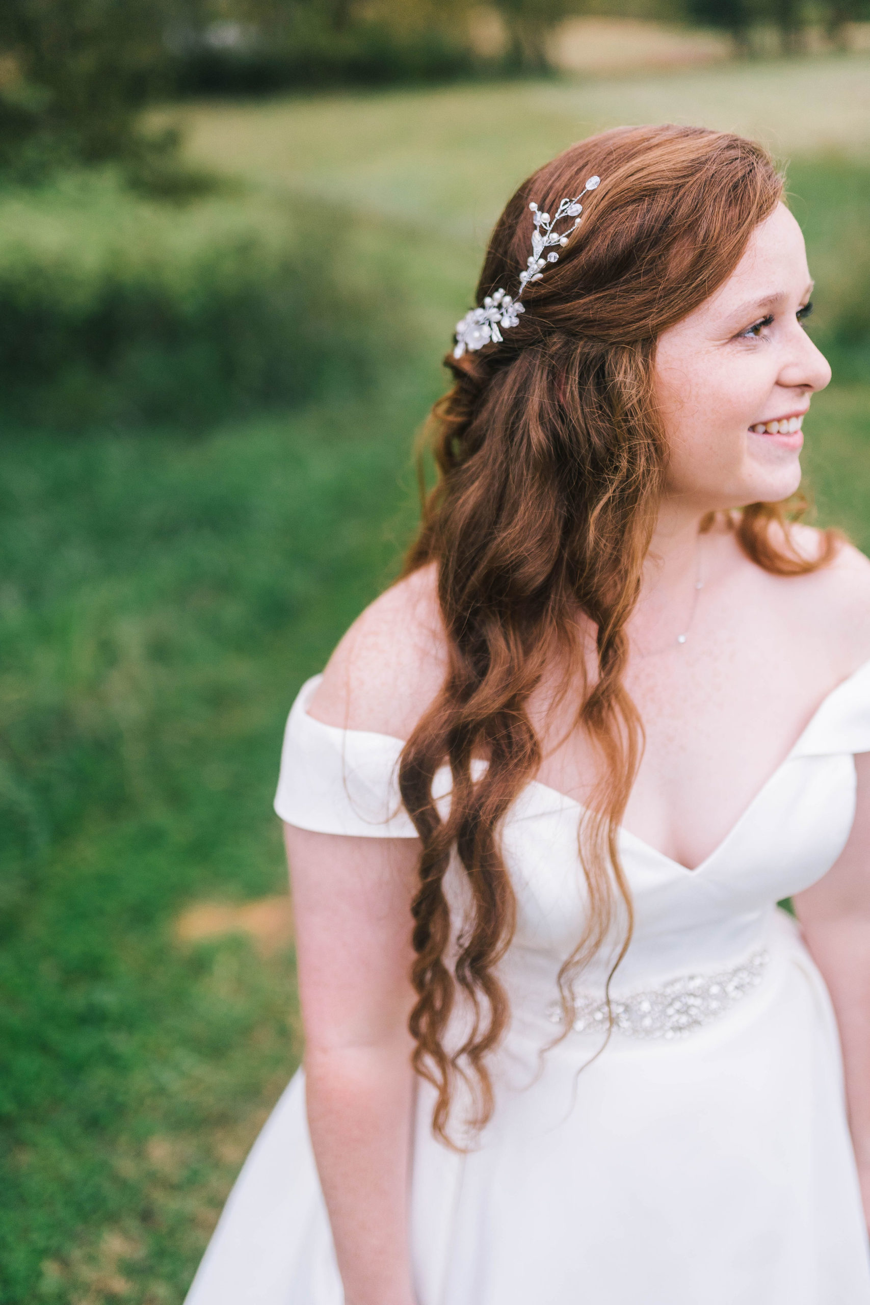 gorgeous shot of a red headed bride on her wedding day. Off the shoulder white satin gown with a beautiful crystal waist detail.