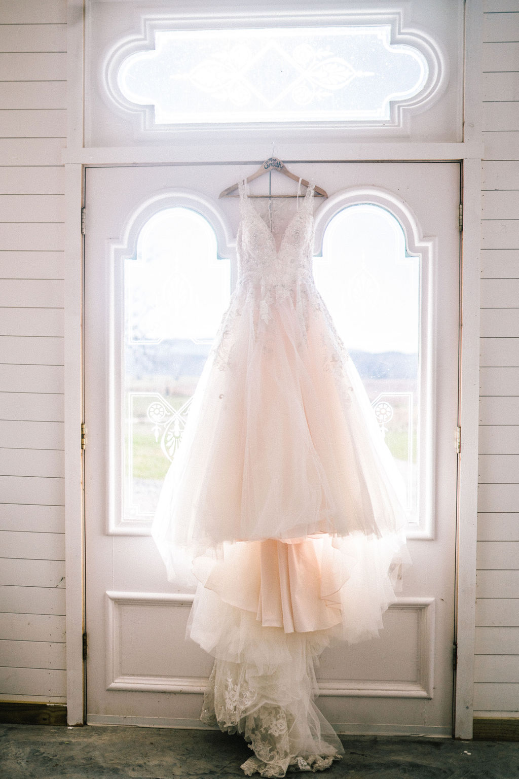 Full length pciture of wedding dress hanging from a door