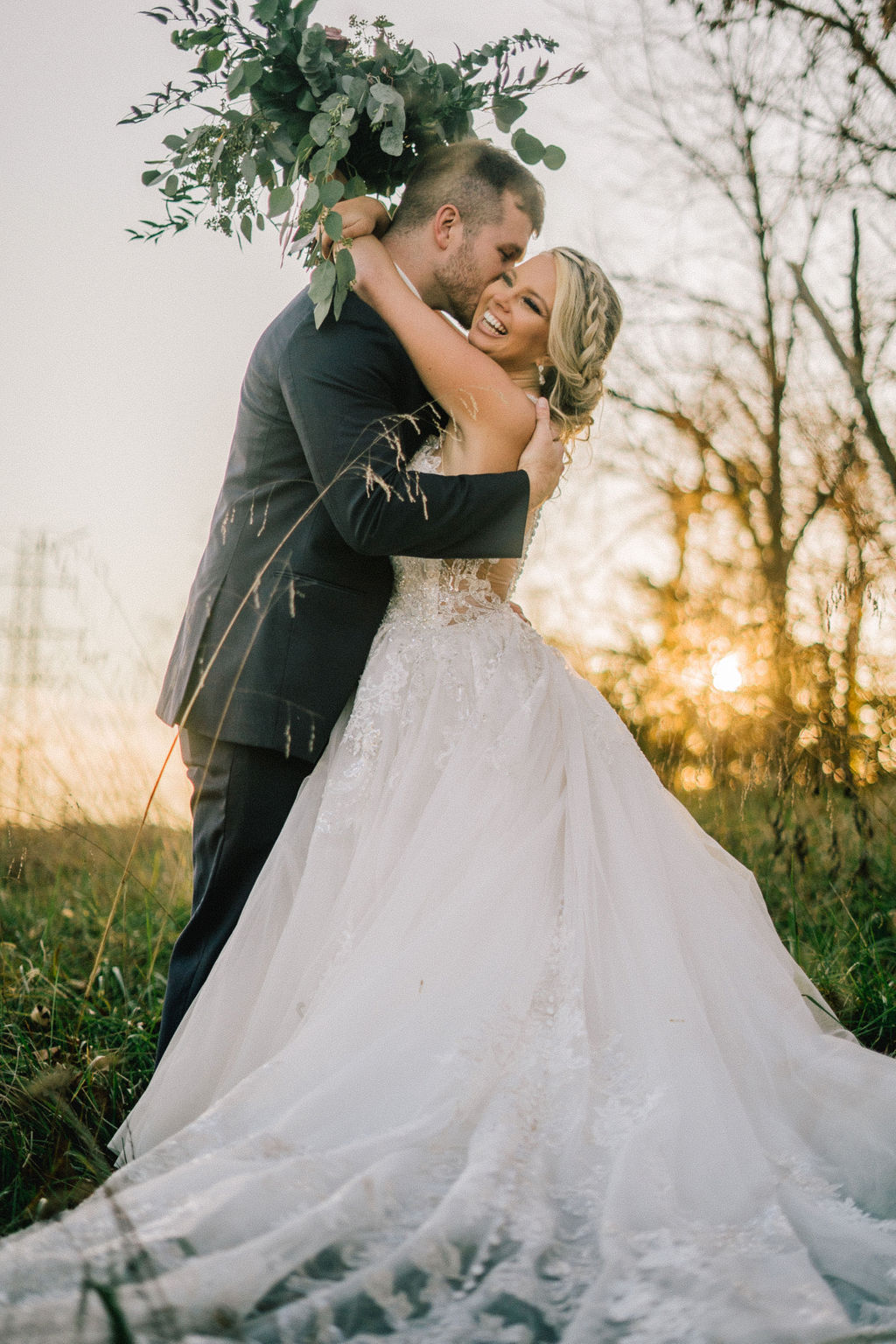 destination wedding planning tips imagery with bride holding her arms around her grooms neck as she laughs and the sun sets behind the couple on their destination wedding day