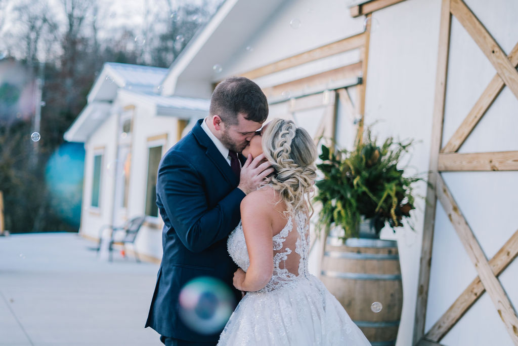 bride and groom kissing celebrating recent marriage at the white barn wedding venue in tennessee
