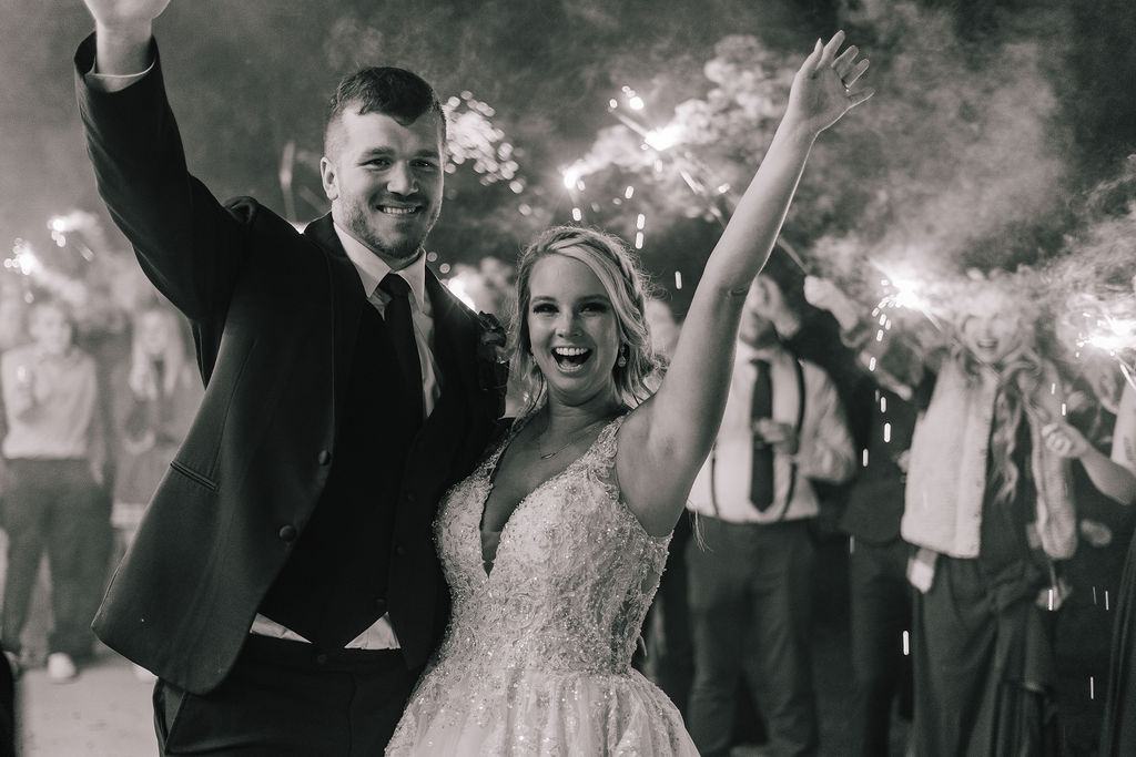 bride and groom celebrating their wedding during a sparkler exit surrounded by all their friends and family