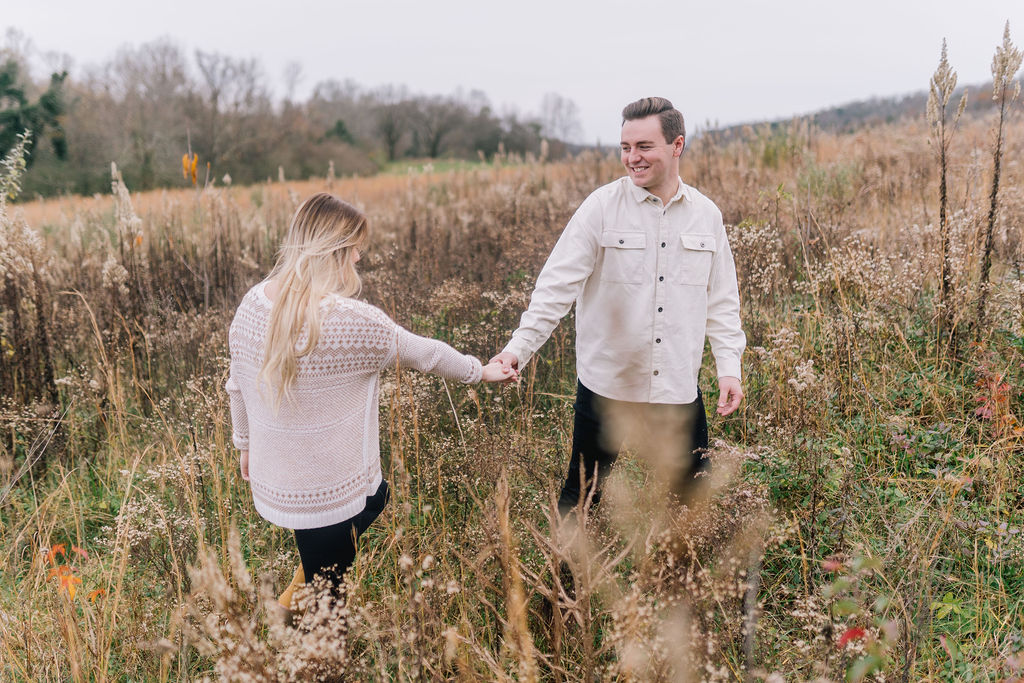man and woman walking through knoxville field after recent engagement surprise proposal