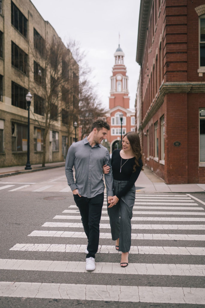 man and woman walking across crosswalk in downtown knoxville during engagements session