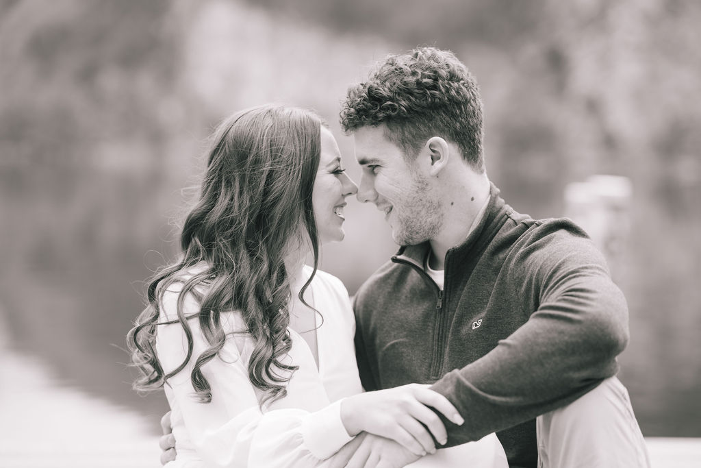 black and white photo of engaged couple sitting next to each other with their noses touching and holding hands for their Knoxville engagement session