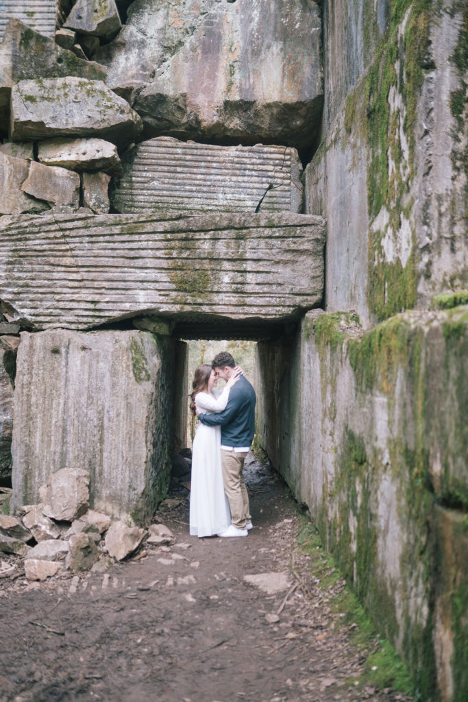 man and woman hugging and kissing under rock arch at meads quarry in knoxville tennessee