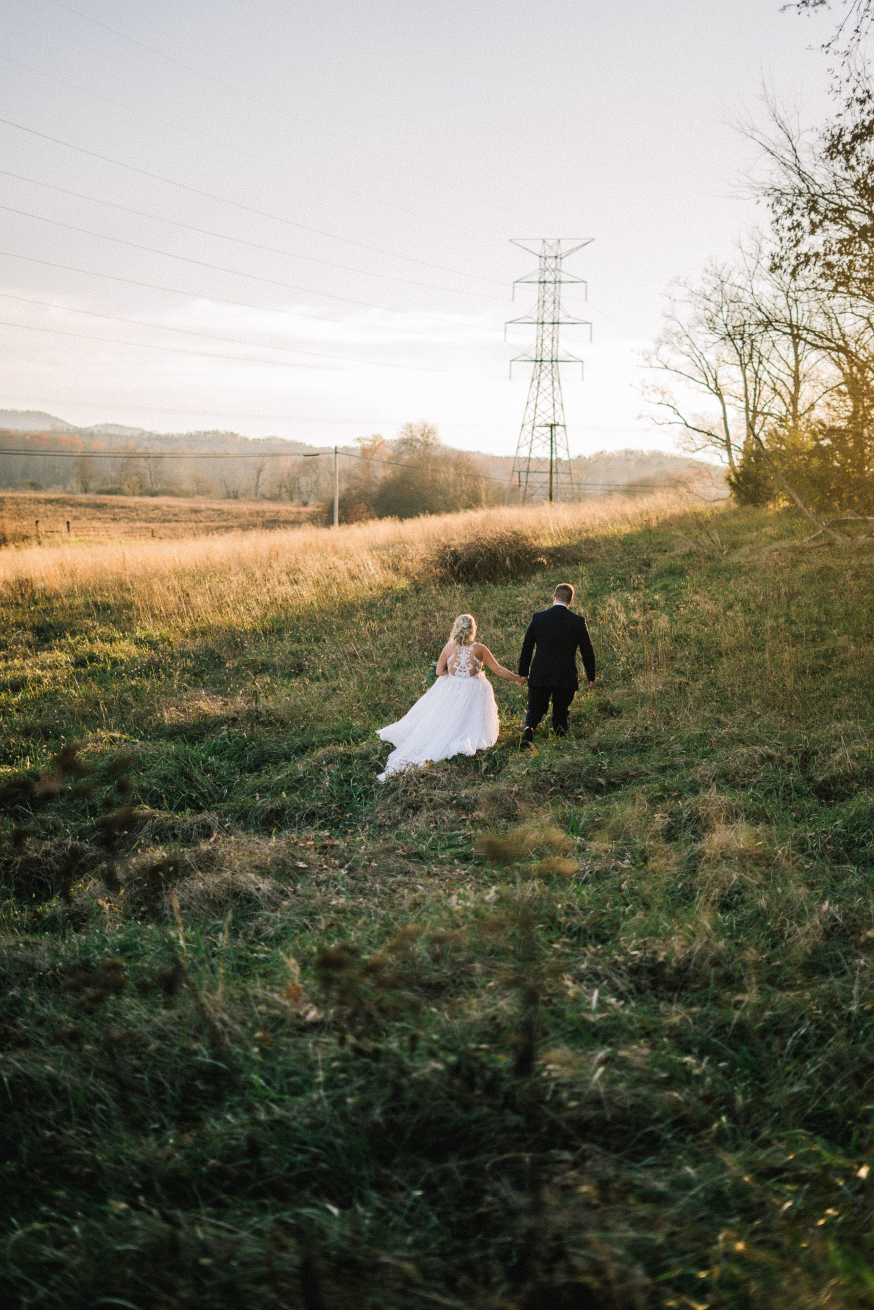 bride and groom walking through a field in tennessee