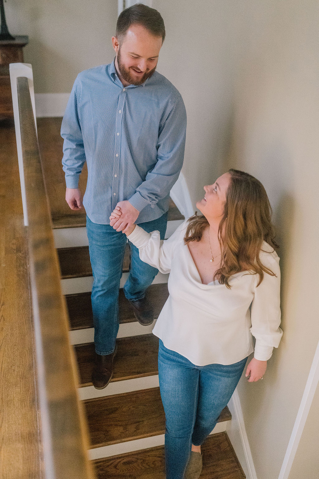in home engagement session in Knoxville Tennessee. Couple walking down the stairs holding hands
