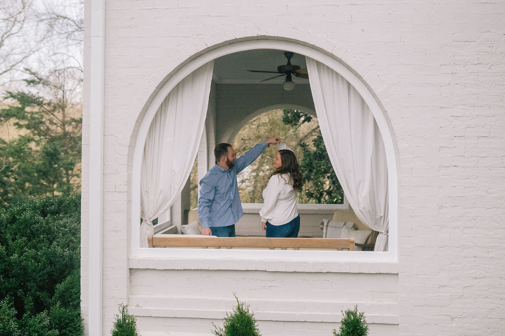 engagement photographer arched window with engaged couple standing inside