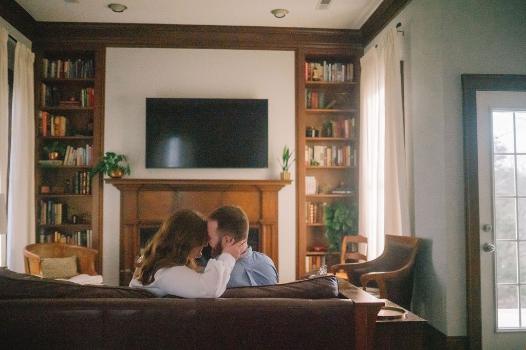 in home engagement session. engaged couple in their living room cuddled on the couch.