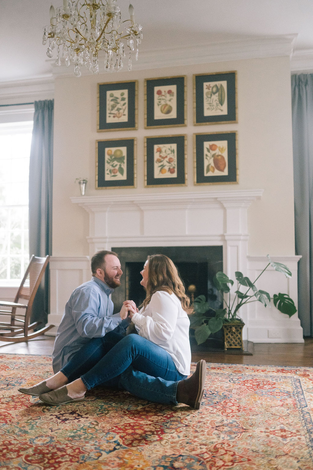 in home engagement session wi the couple sitting on the living room floor while holding hands