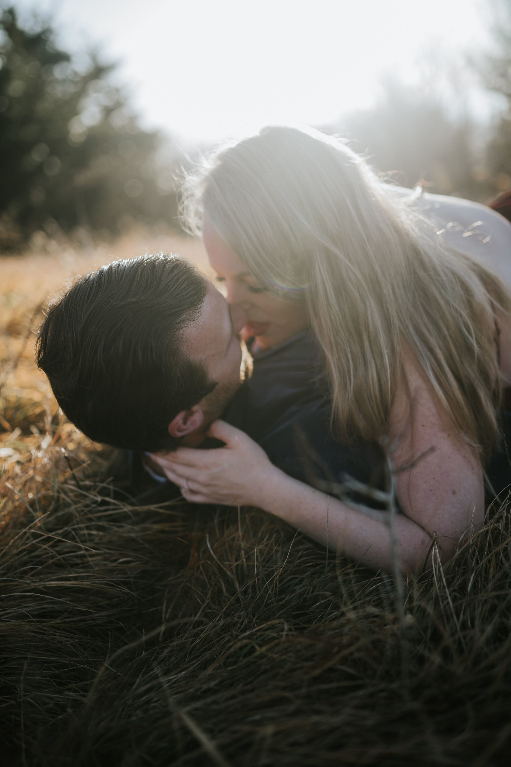 smoky mountain honeymoon session with bride laying on top of her groom kissing him in a fall field at sunset
