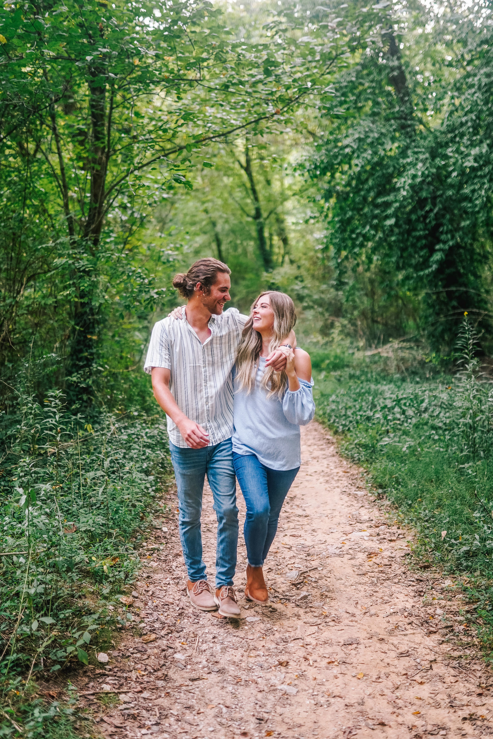 smoky mountain engagement photos. Couple walking through the gorgeous lush forest on a dirt trail.