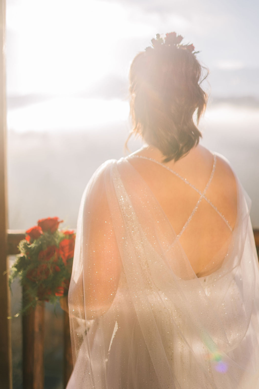 the light gleams through the fog as the smoky mountain bride looks into the distance, showing the detail of her open back wedding gown