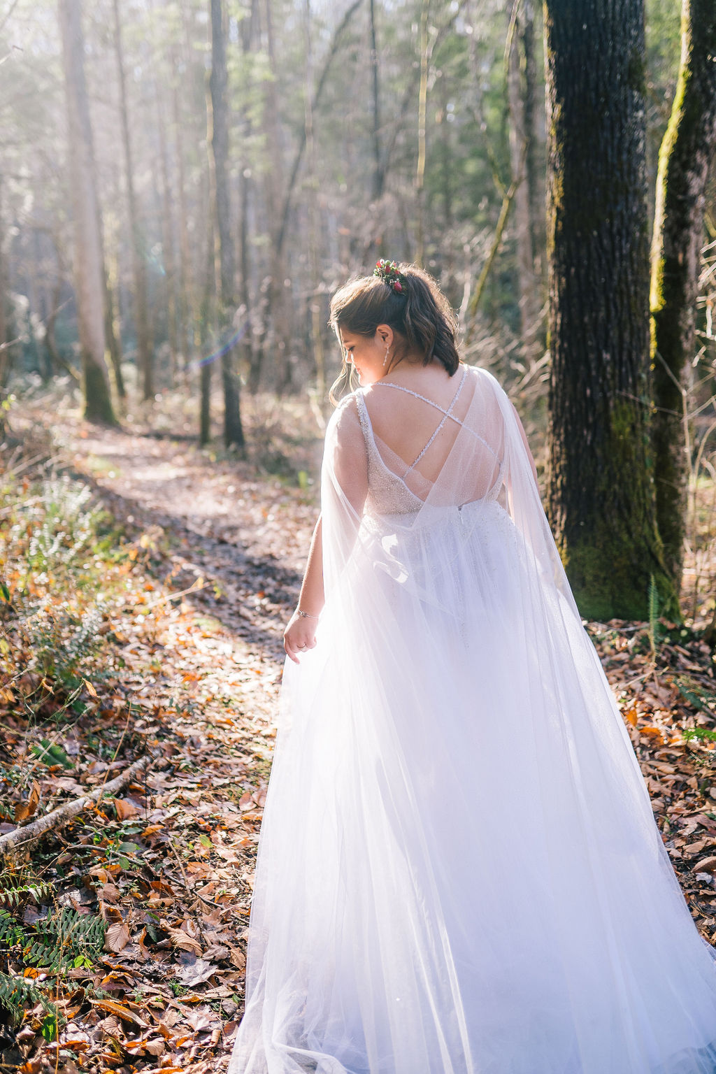 whimsical bride walking through the forest on her wedding day in the smokies as her long cape drags behind her