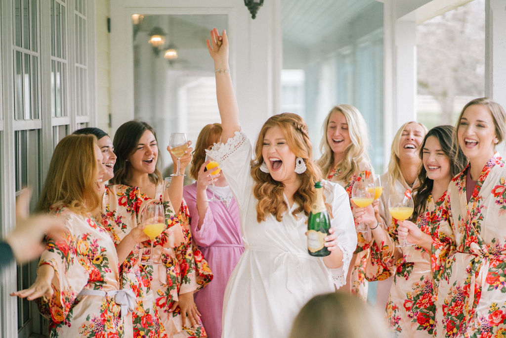 bride popping the champagne with her bridesmaids on her wedding day at Marblegate Farms in Tennessee for a special moment