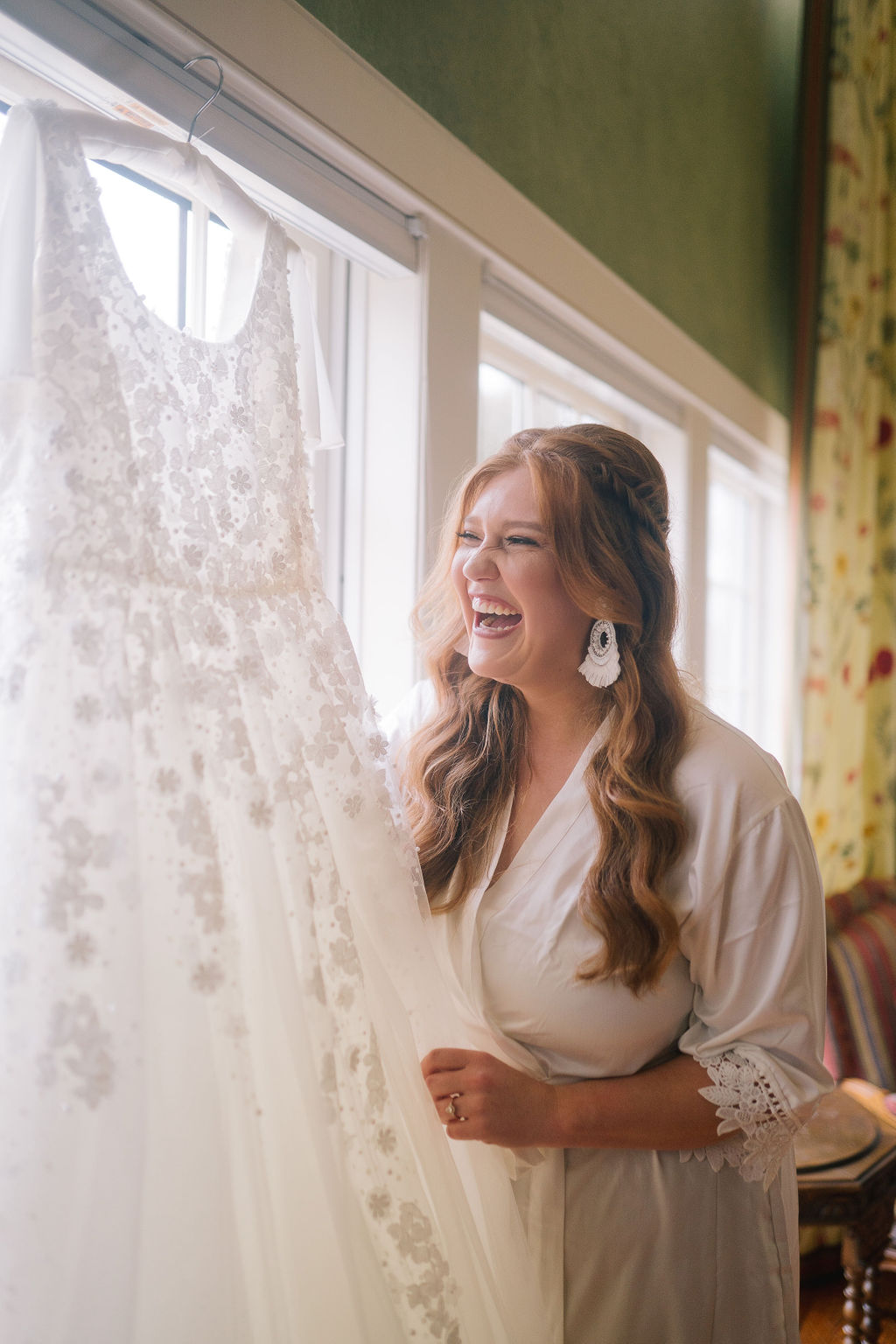tennessee bride holding her wedding dress outside a bright window in her brides room smiling