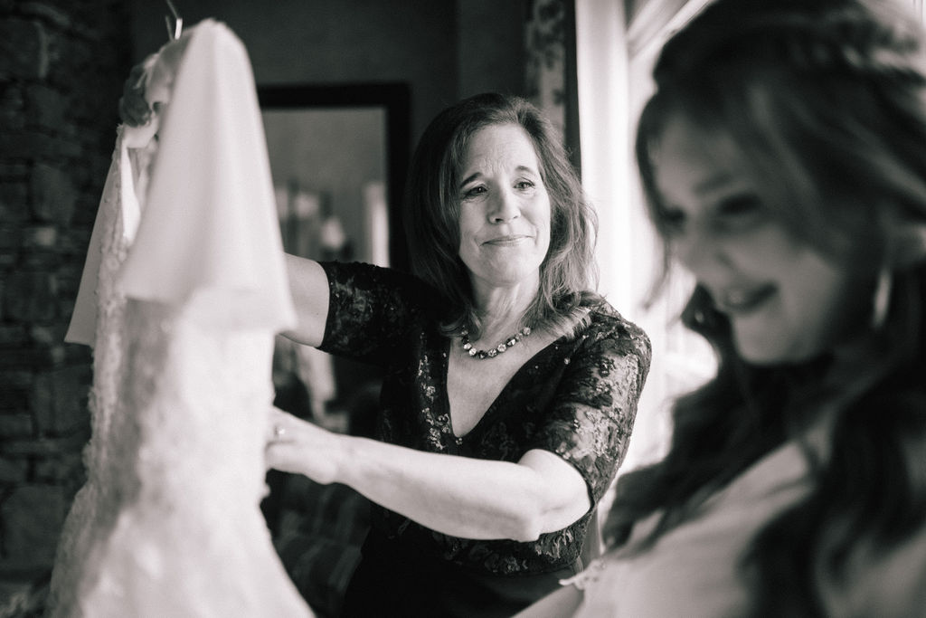 black and white photo of mother and daughter on wedding day at Marblegate Tennessee. Mother holding daughters wedding dress and looking at her with tears in her eyes