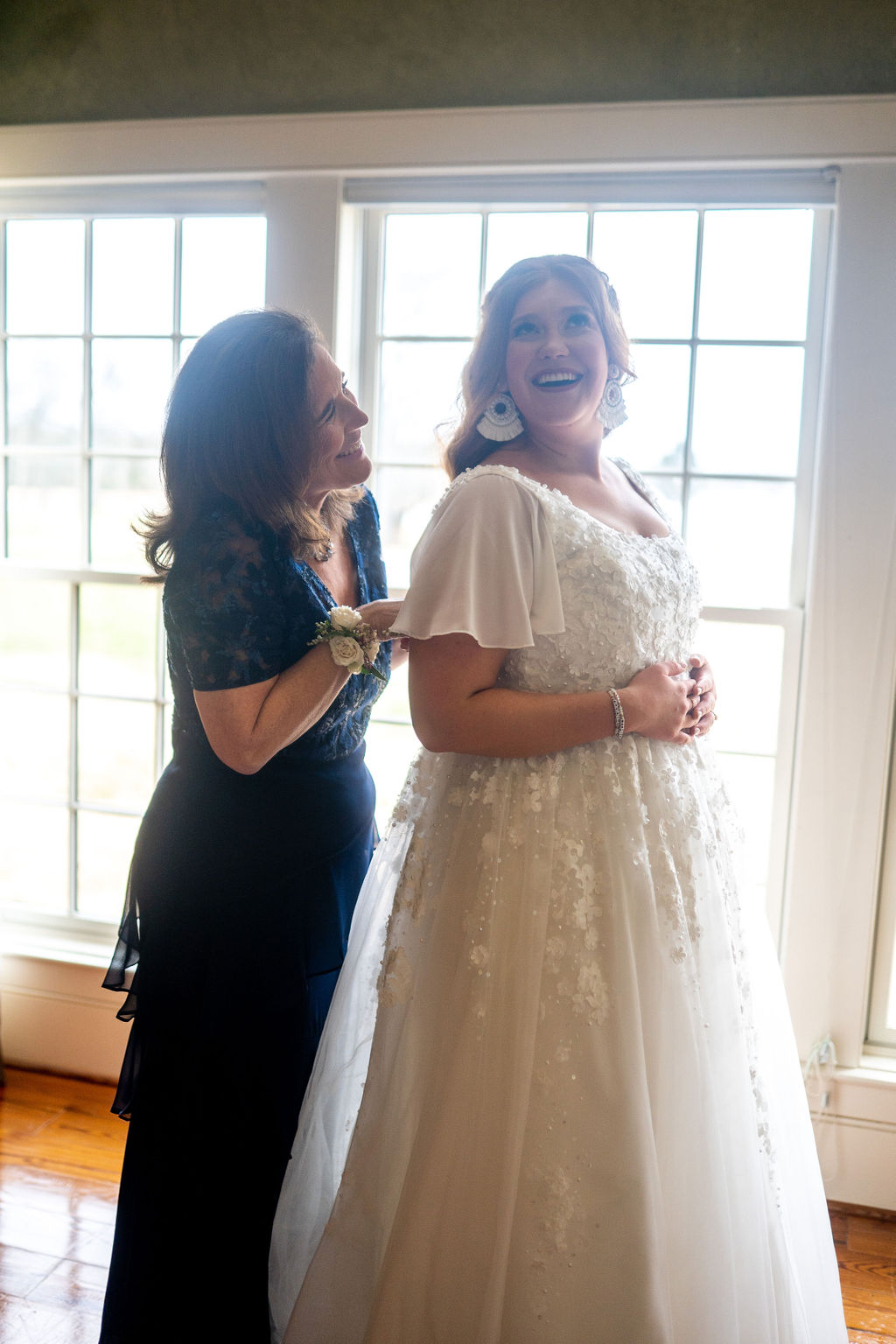 mother and daughter laughing in front of a bright window on her wedding day at MArblgate farms in Tennessee as they get ready for the brides wedding day