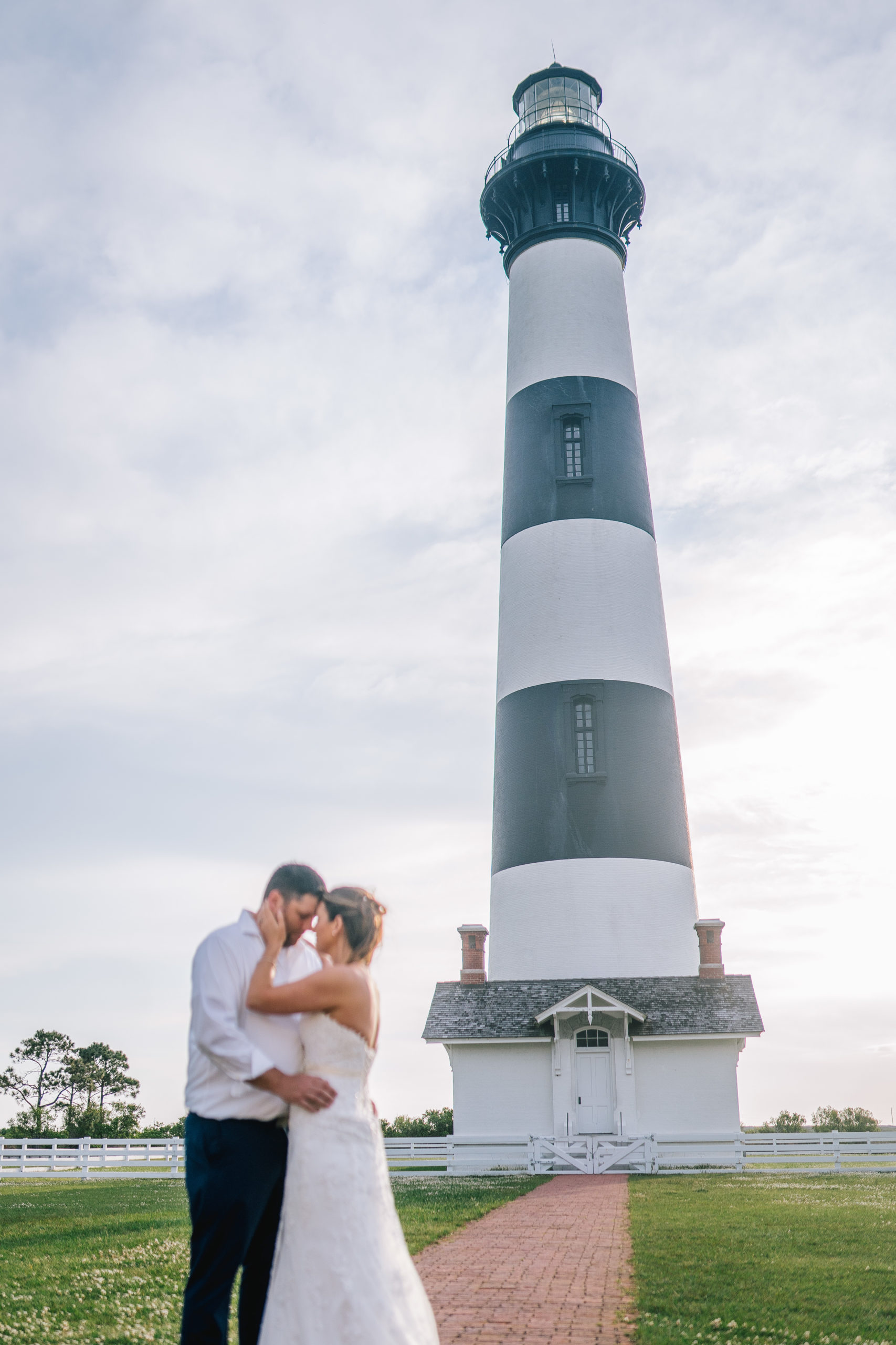 adventure lighthouse session. bride and groom are embracing eachother on the east coast in front of a lighthouse
