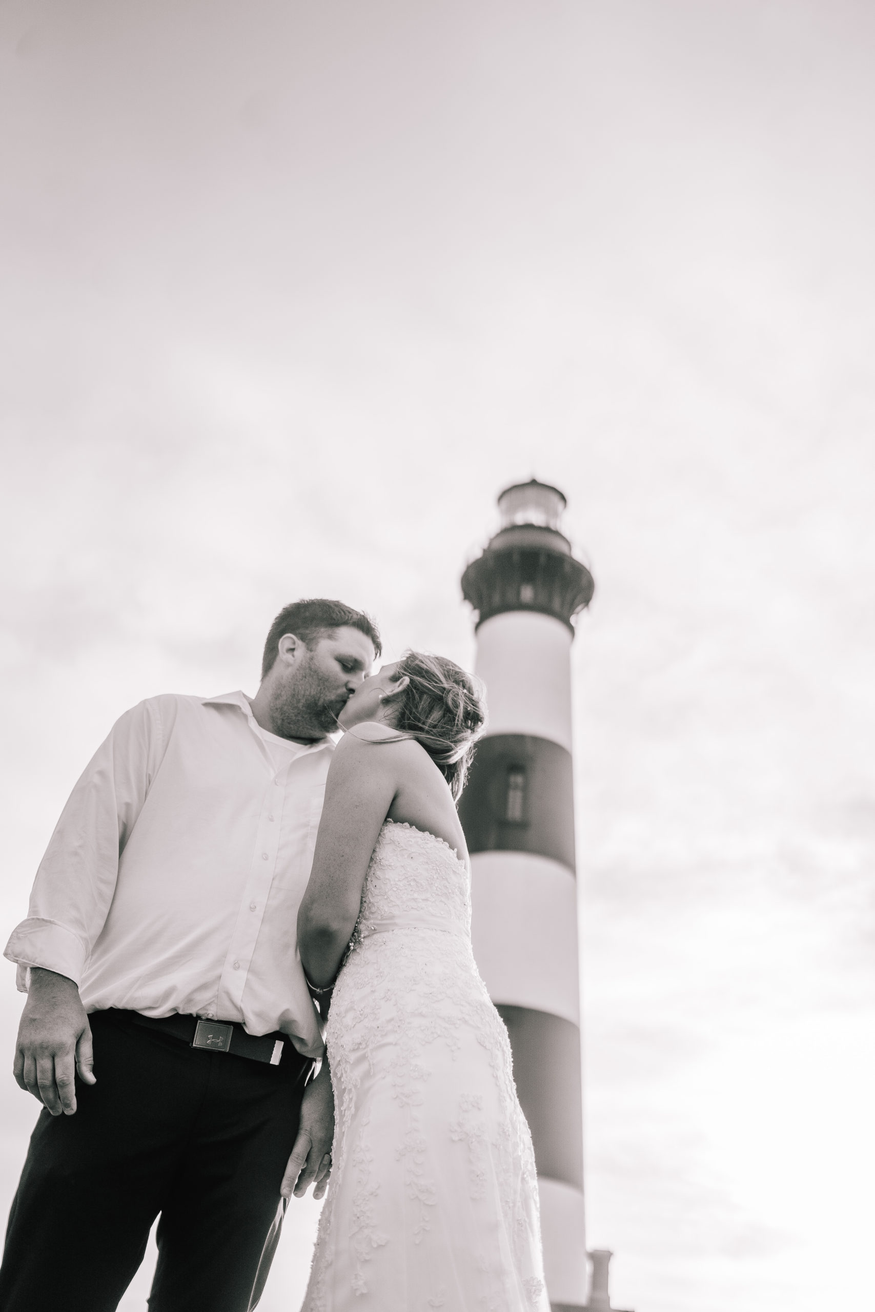 black and white photo of a wedding couple in front of a lighthouse