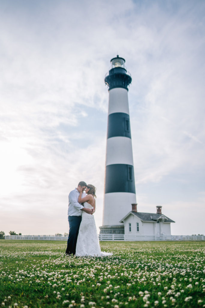 lighthouse adventure session on the east coast for a wedding day. bride and groom embrace each other right in front of a lighthouse early in the morning