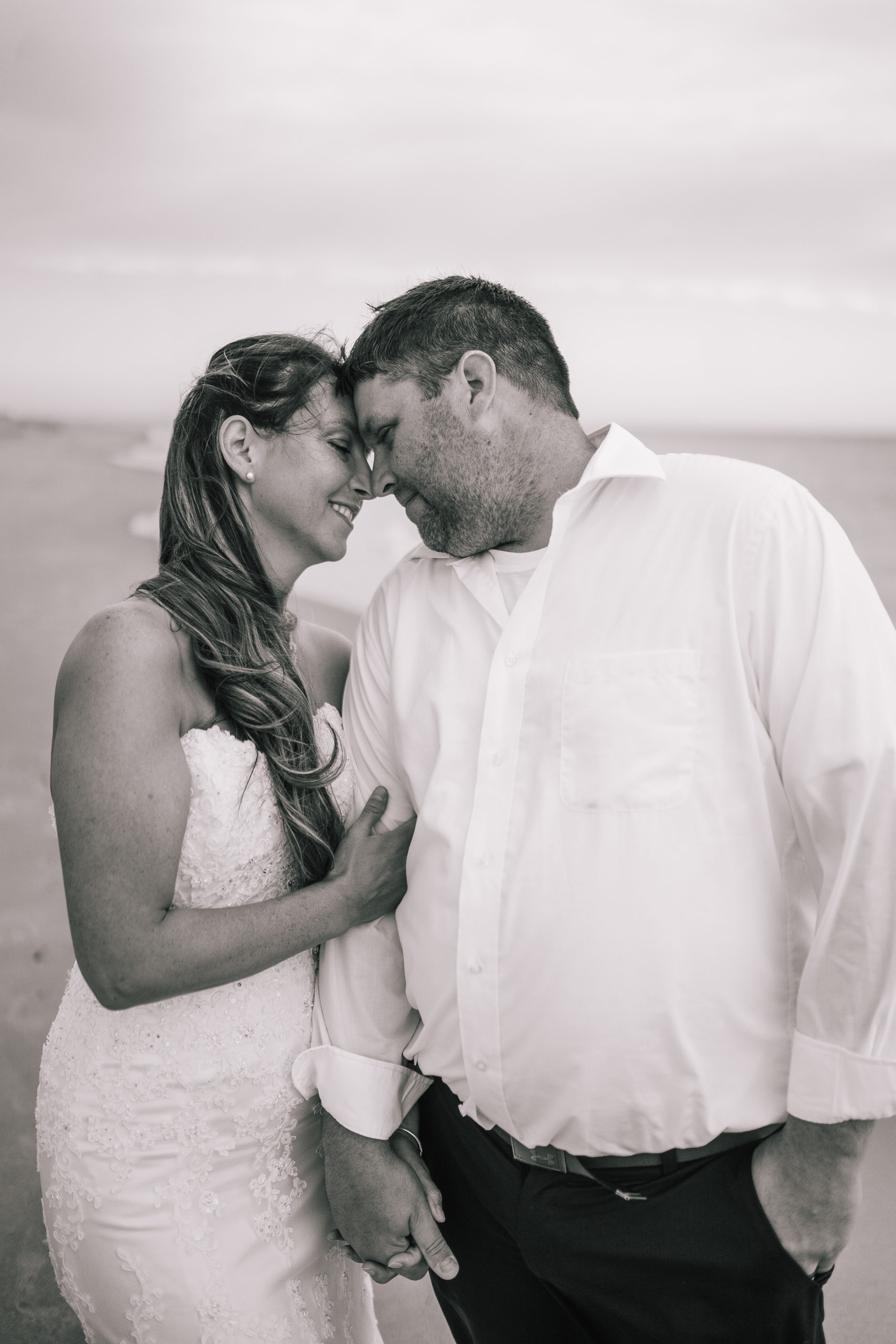 black and white photo of bride and groom gazing into each others eyes on their beach wedding day