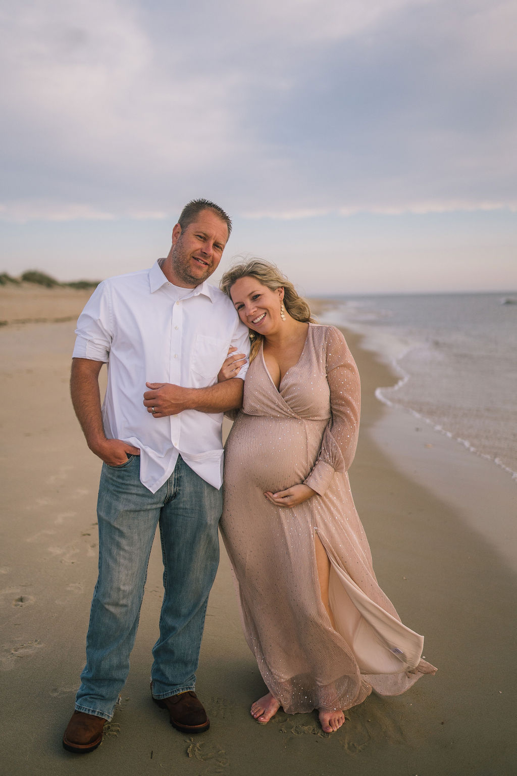 man and woman on the beach in the morning holding each other. Maternity shoot at the Outerbanks.