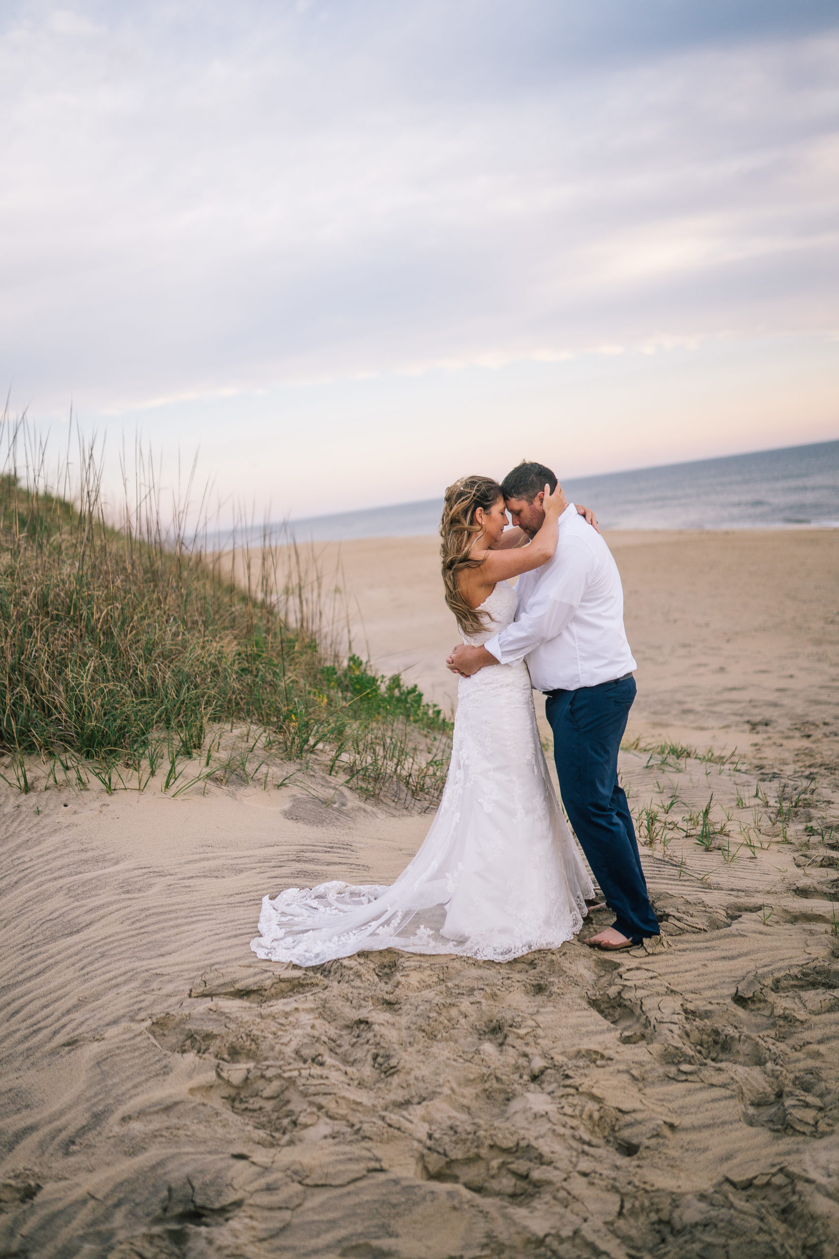 East Coast bride and groom holding eachother as they stand on the beach