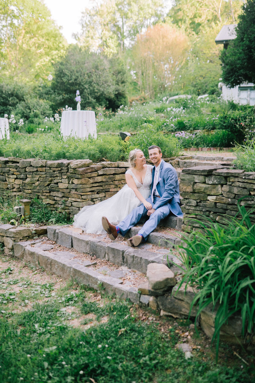 wedding day couple sitting on stone stair int eh middle of an Ijams garden holding each other