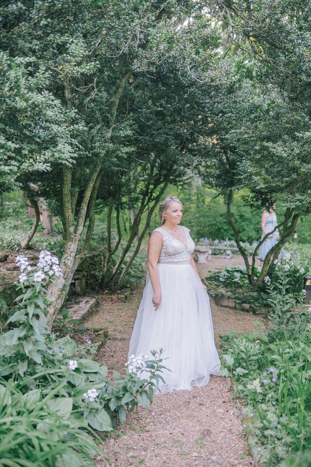 bride standing on a trail in the Ijams in her wedding dress from Vowed with a lush garden surrounding her
