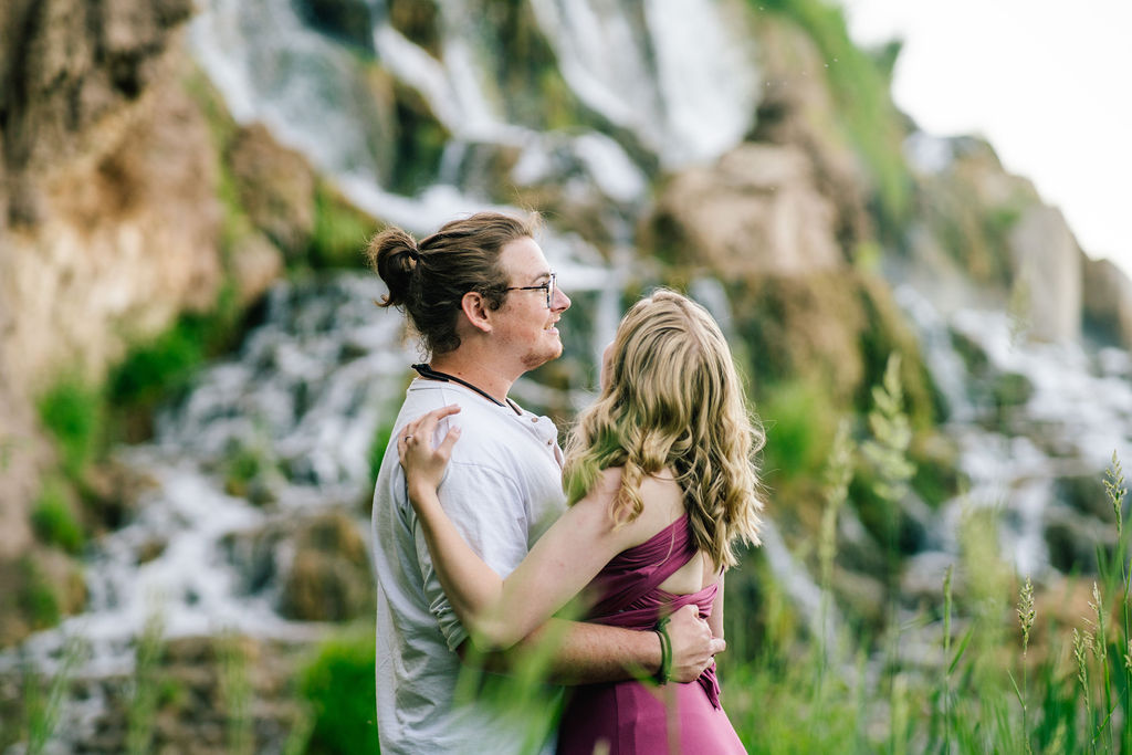 adventure engagement session with man in a white shirt and woman in a purple dress slow dancing together next to the waterfall in Tennessee's Smokey Mountains 
