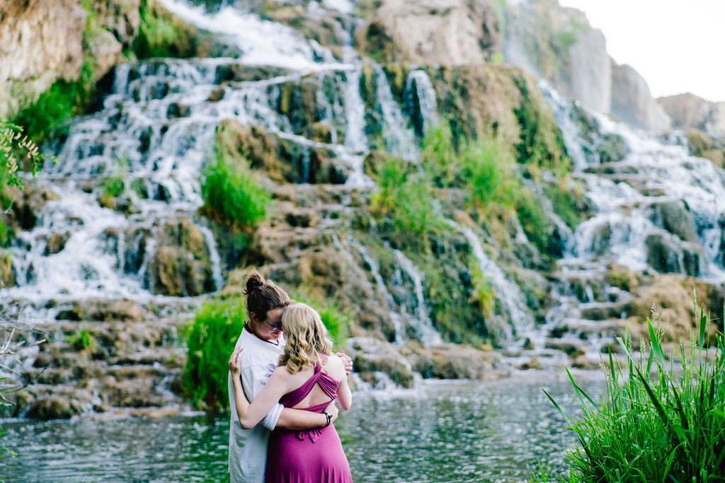 waterfall engagement inTennessee with man and woman dancing in a pond next to a waterfall romantically 