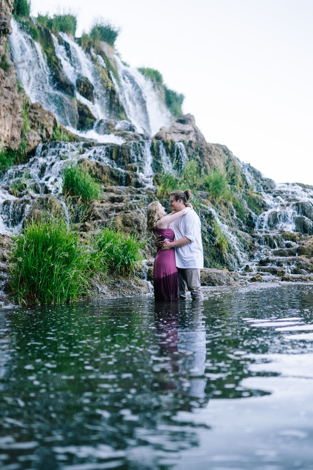 man and woman standing gin a pond in the Smokies and hug each other for their outdoor engagement photos