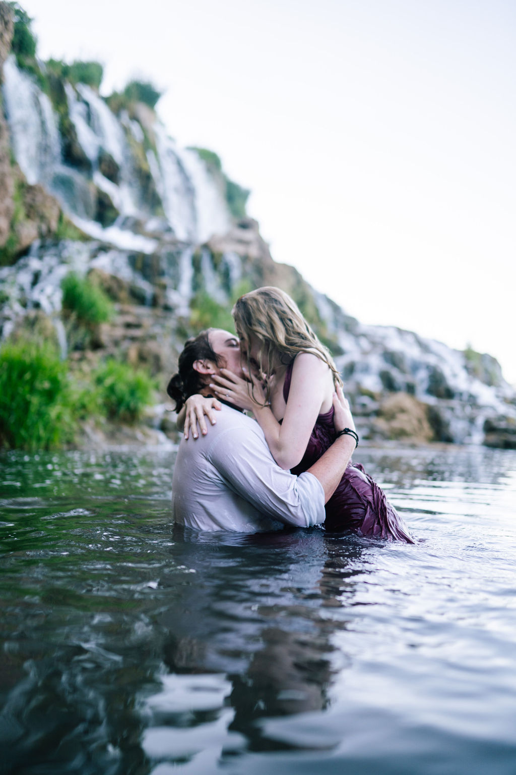 man and woman in the lake by a waterfall in Tennessee making out for their engagement photos