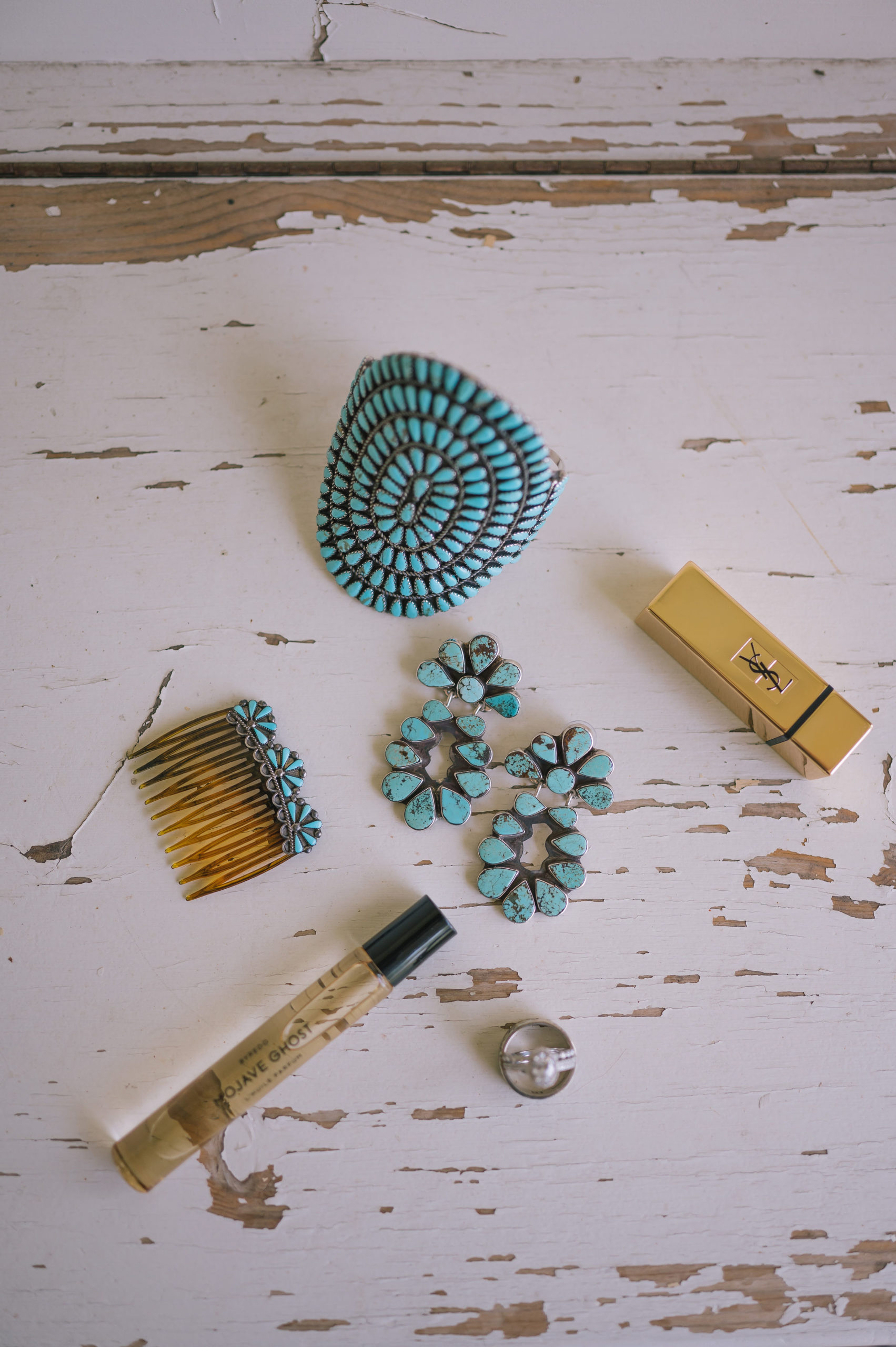bridal wedding flatlay with turquoise rings and necklaces as well as some perfume and lipstick
