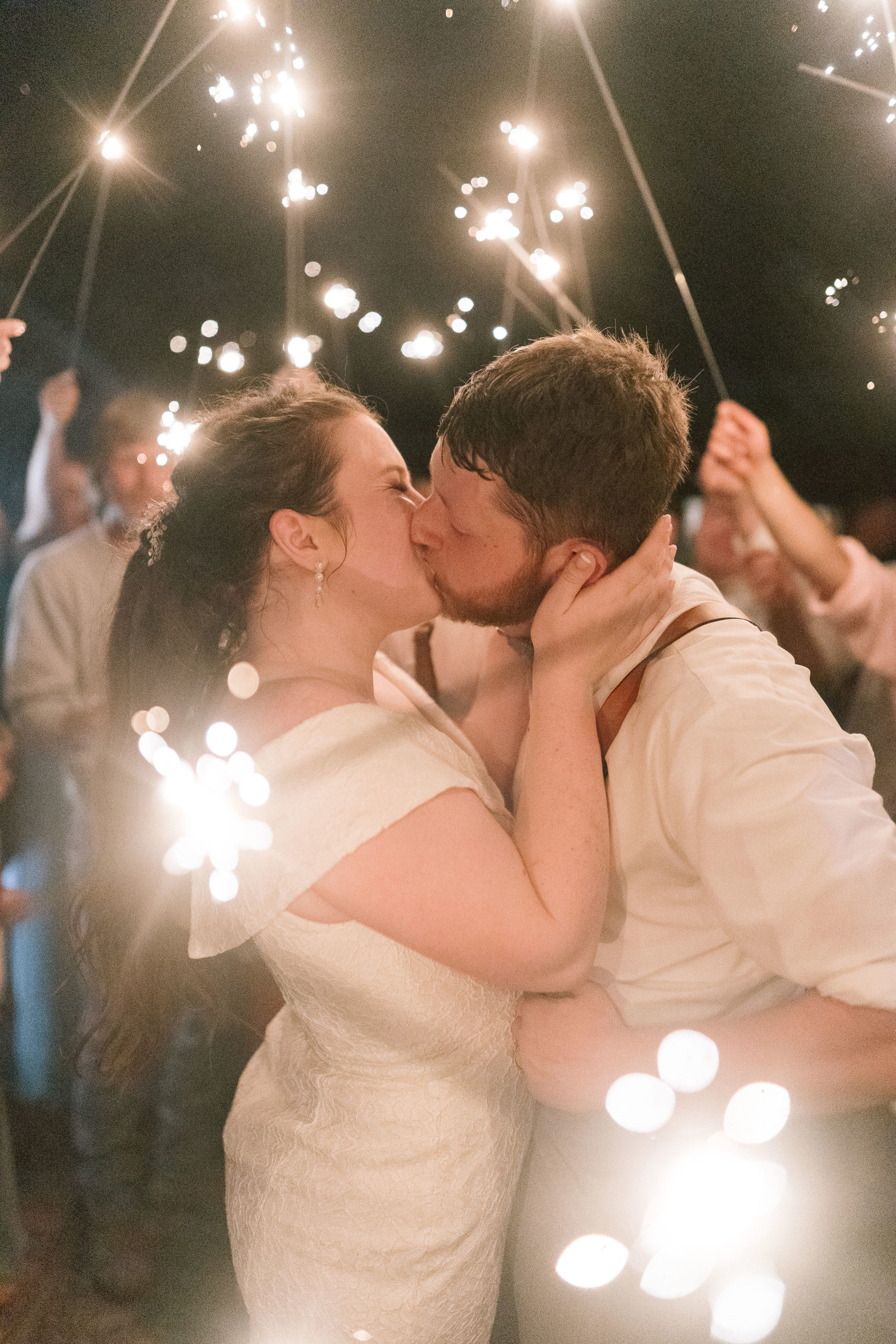 bride and groom kissing passioantely int he middle of a bunch of sparklers at the end of their wedding day for their send off