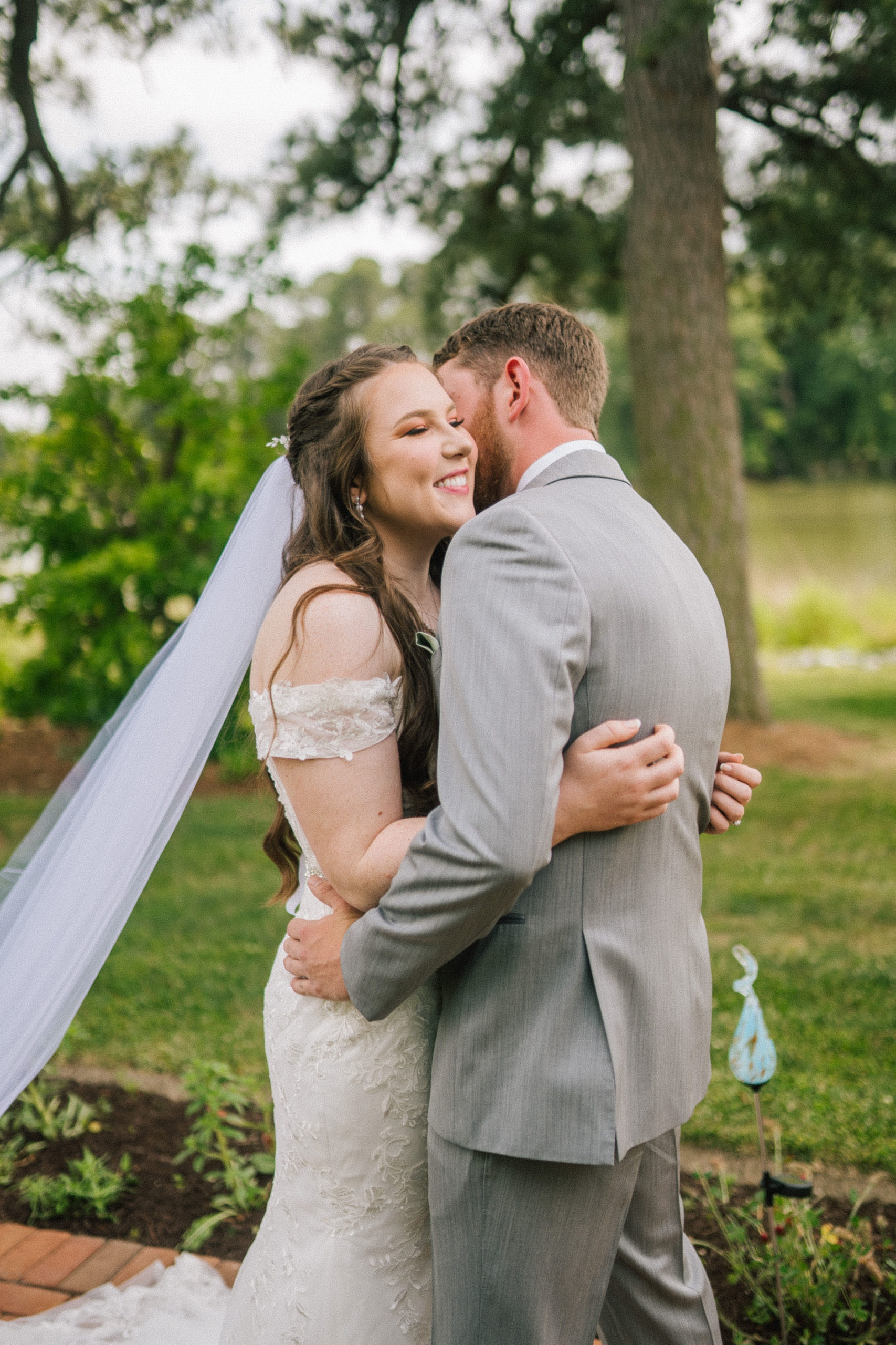 Maryland bride and groom embrace each other and their water front wedding venue as the bride smiles while her veil flows behind her in the wind