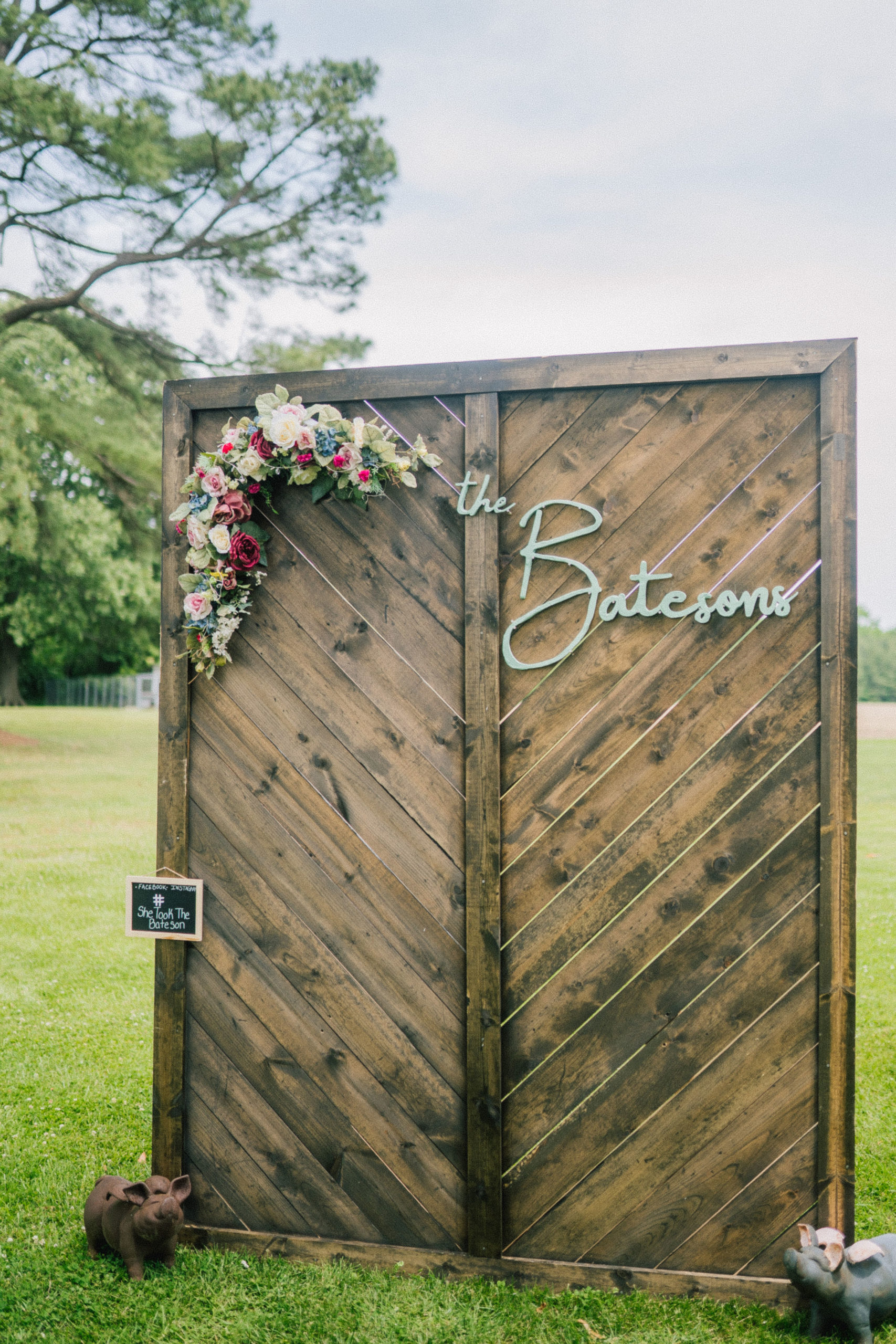 wedding decor at a Maryland destination wedding in the spring time, tall wooden palette board with florals and the family's last name in script