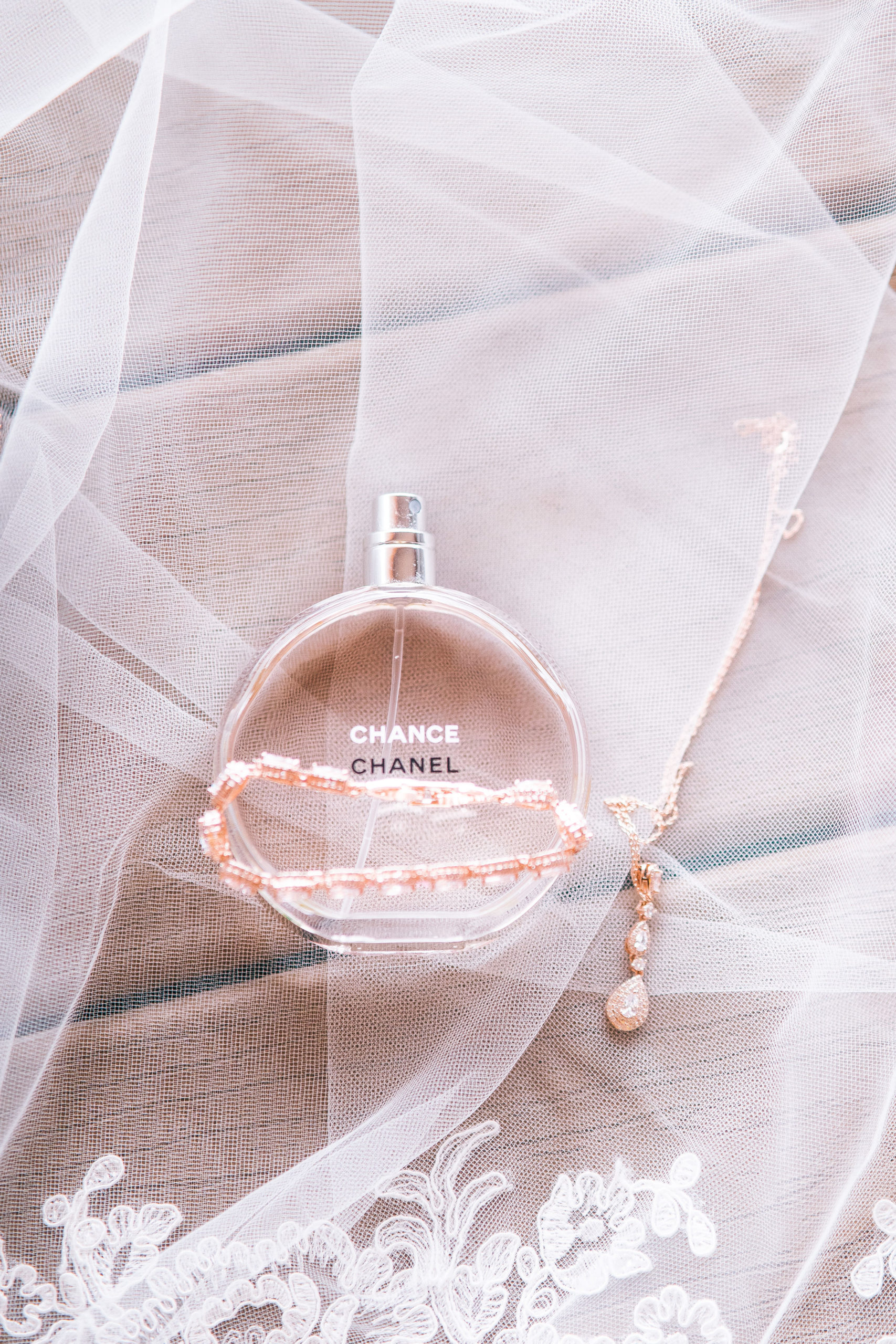 brides perfume laying on top of her veil with her bracelet draped over the bottle