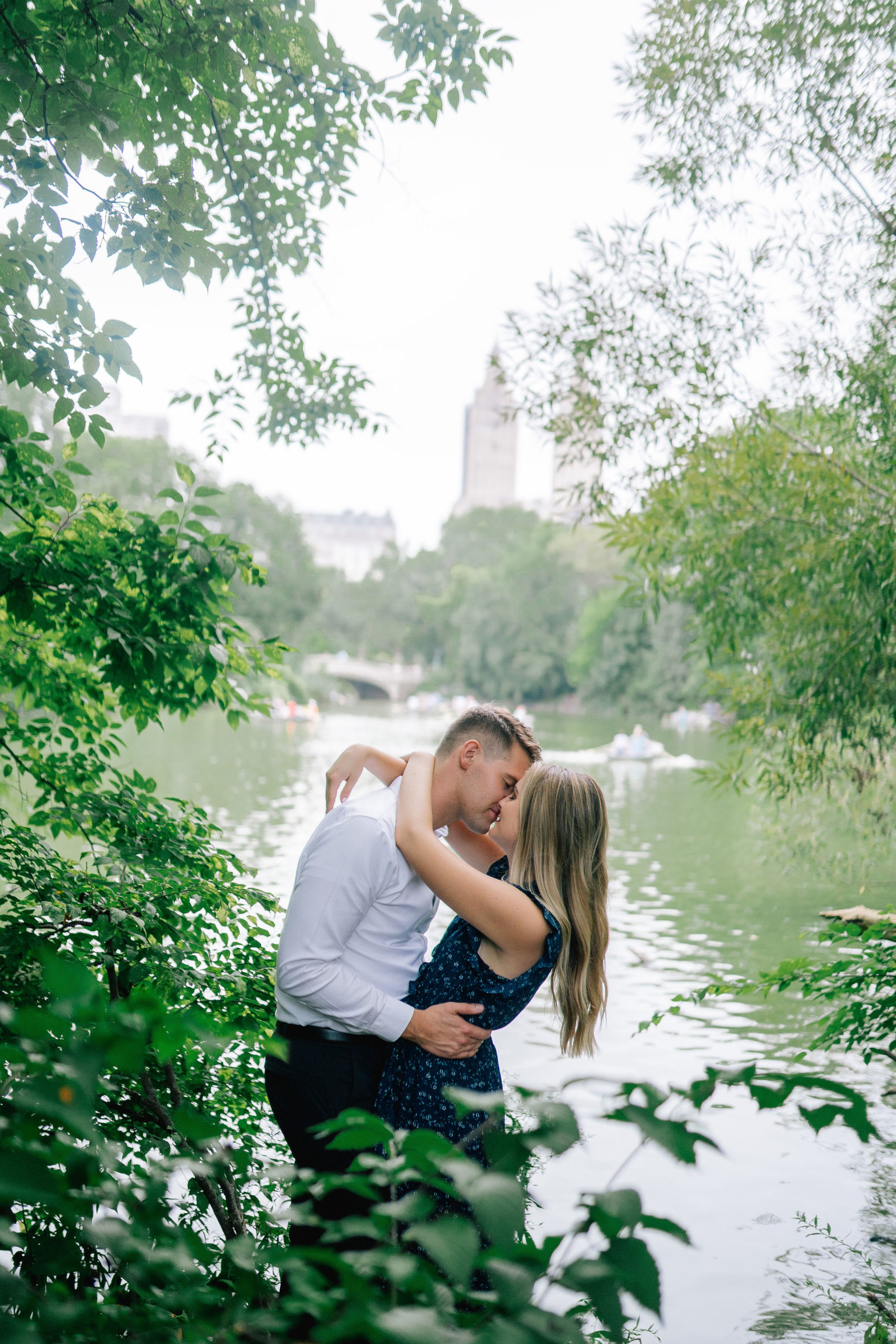 passionate kiss between an engaged couple as they stand in the tree line in central park for their engagement session