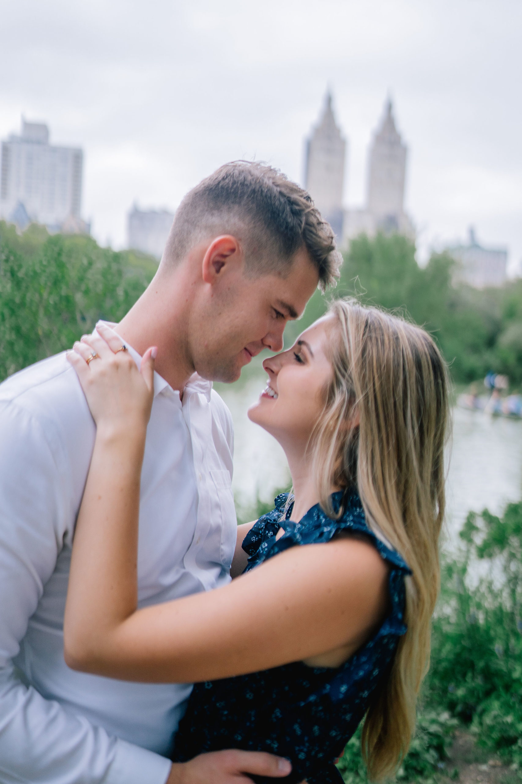 close up shot of man and woman holding each other and slightly smiling right before they kiss in Central Park in New York City