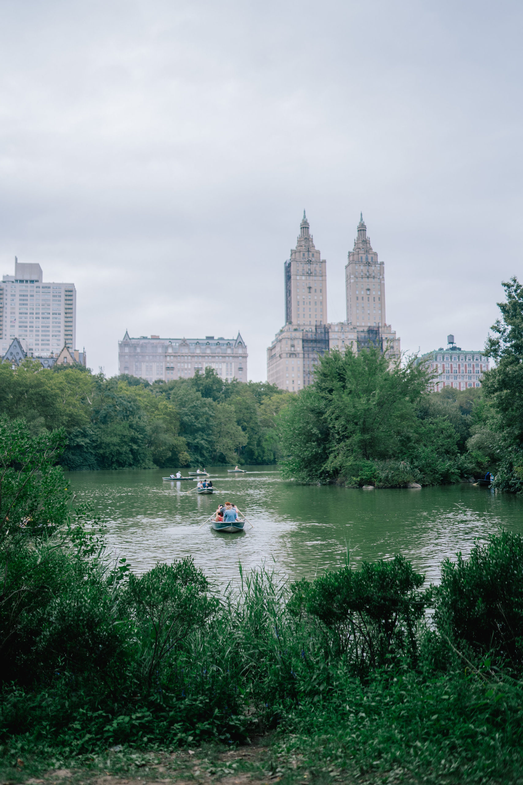 cityscape of NYC from Central Park near the Loeb Boathouse with a view of the pond and row boats