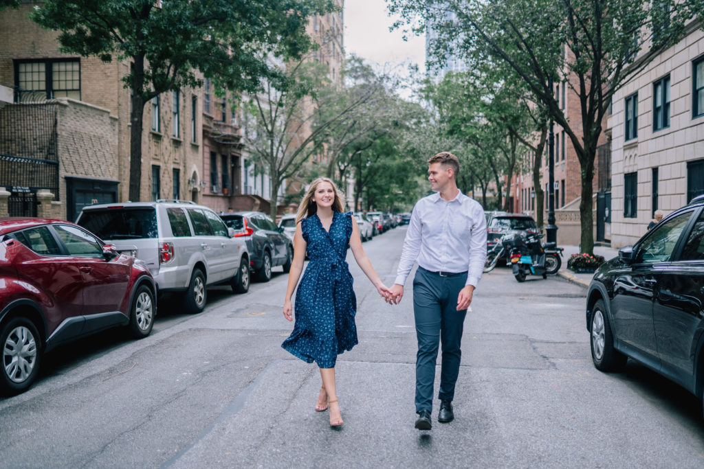 engagement session on the streets of NYC in Brooklyn with the nest New York City wedding photographers with man and woman holding hands and walking towards the camera in the middle of the road 