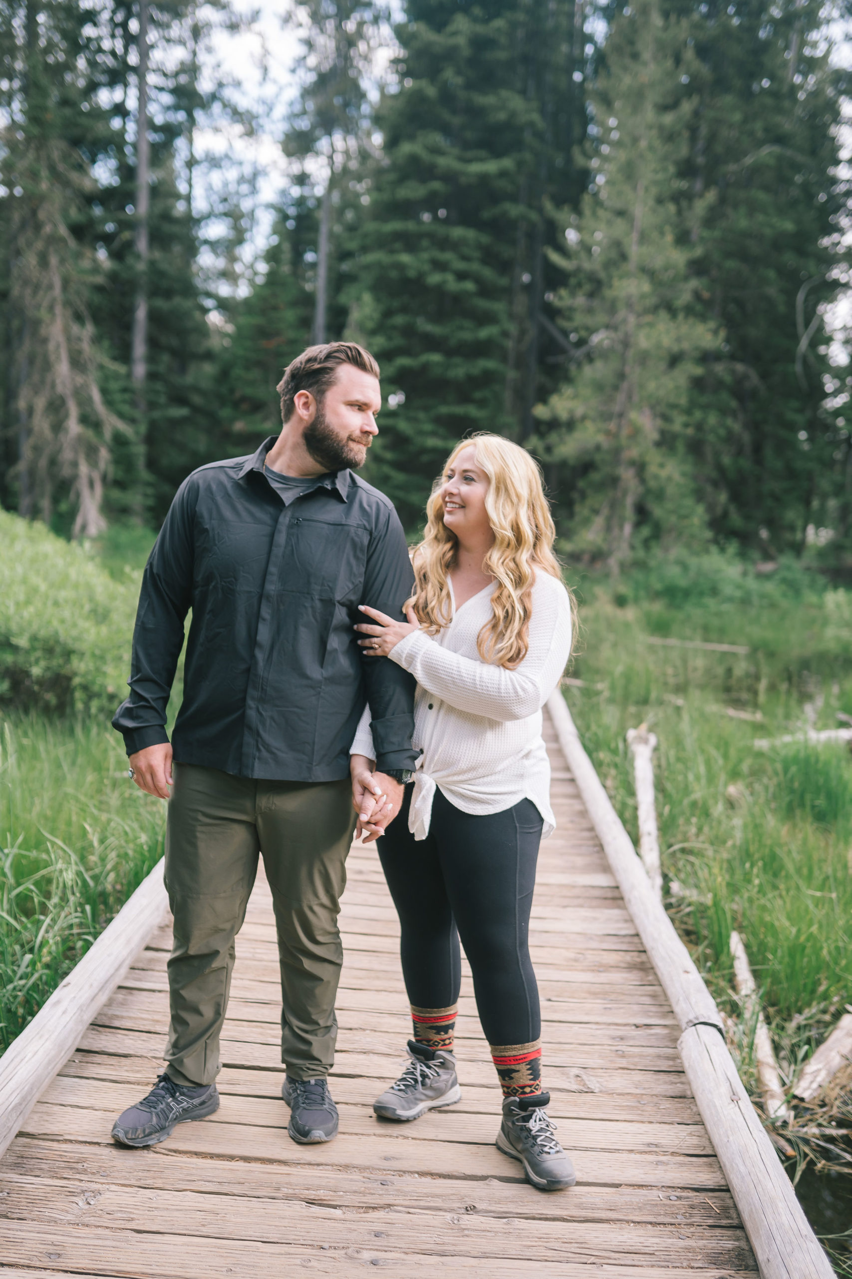 engagement pictures in the Smoky Mountains casual winter engagement photo outfits with man and woman walking on a dock together towards the camera and holding hands while smiling at one another