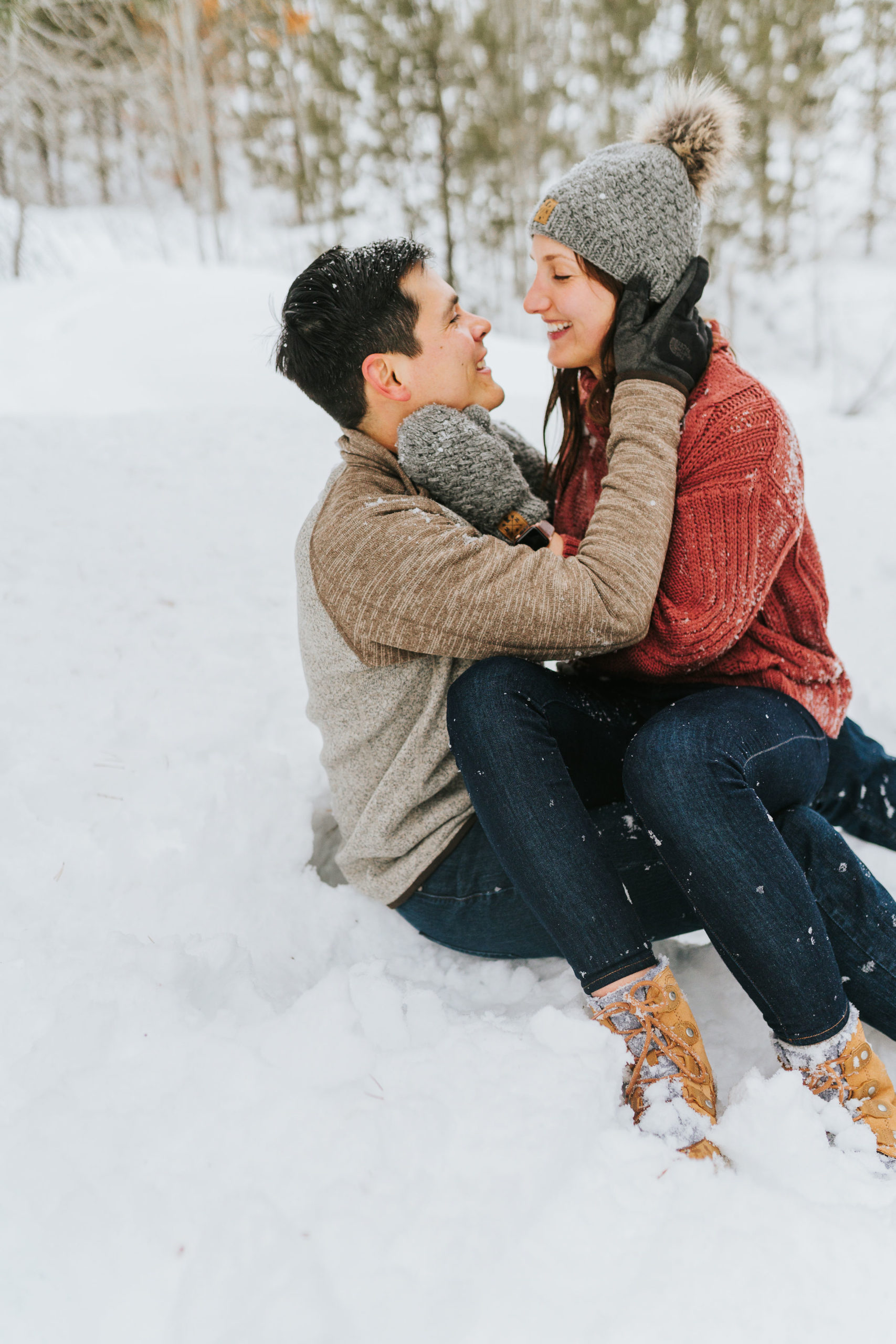 casual winter engagement photo outfits inspo with man and woman playing in the snow and rolling around for a fun and adventurous winter engagement session with the best Smoky Mountain wedding photographers