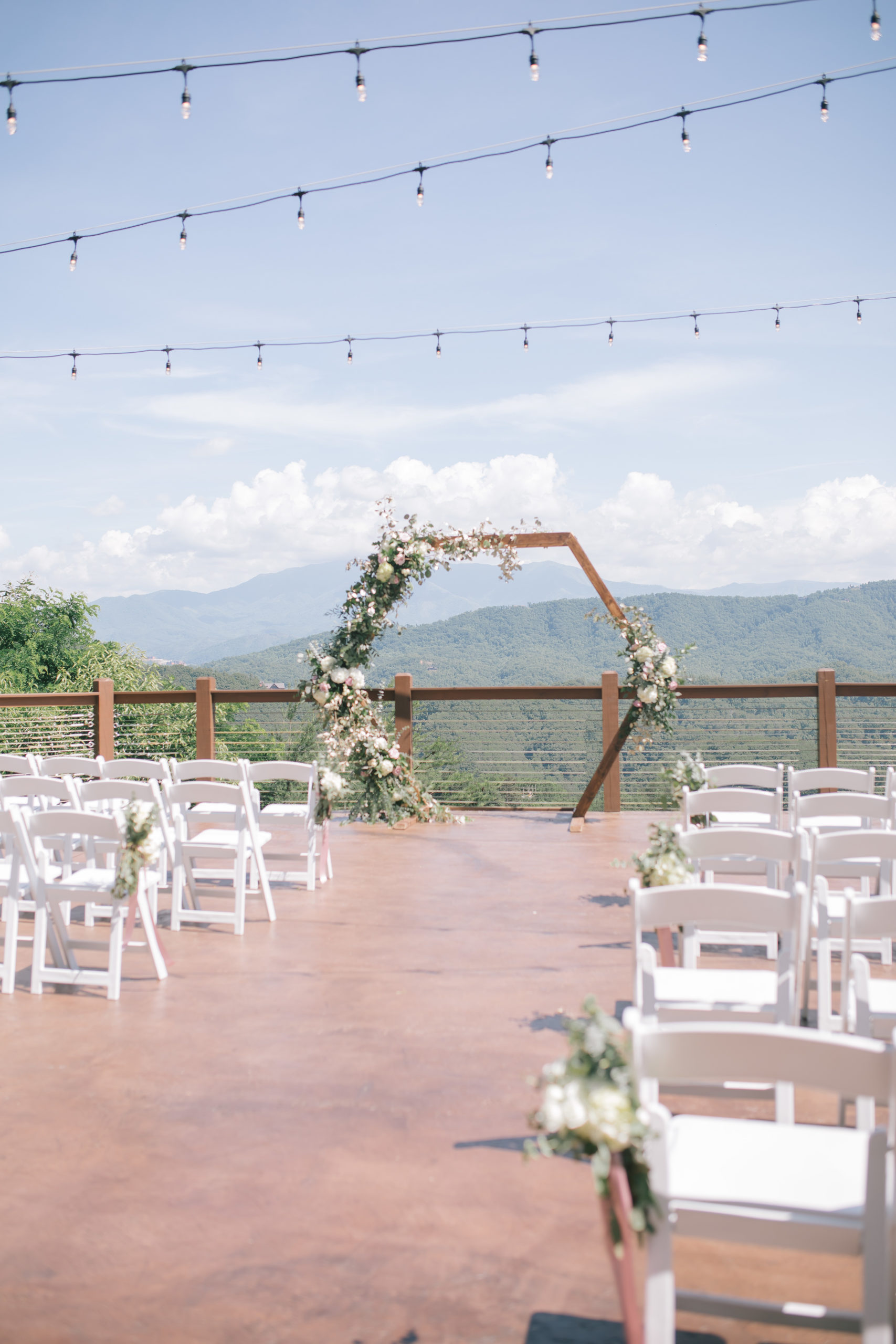 the patio at The Magnolia wedding venue Pigeon Forge with the Smoky Mountains in the distance and a beautiful hexagon wedding arch covered in florals