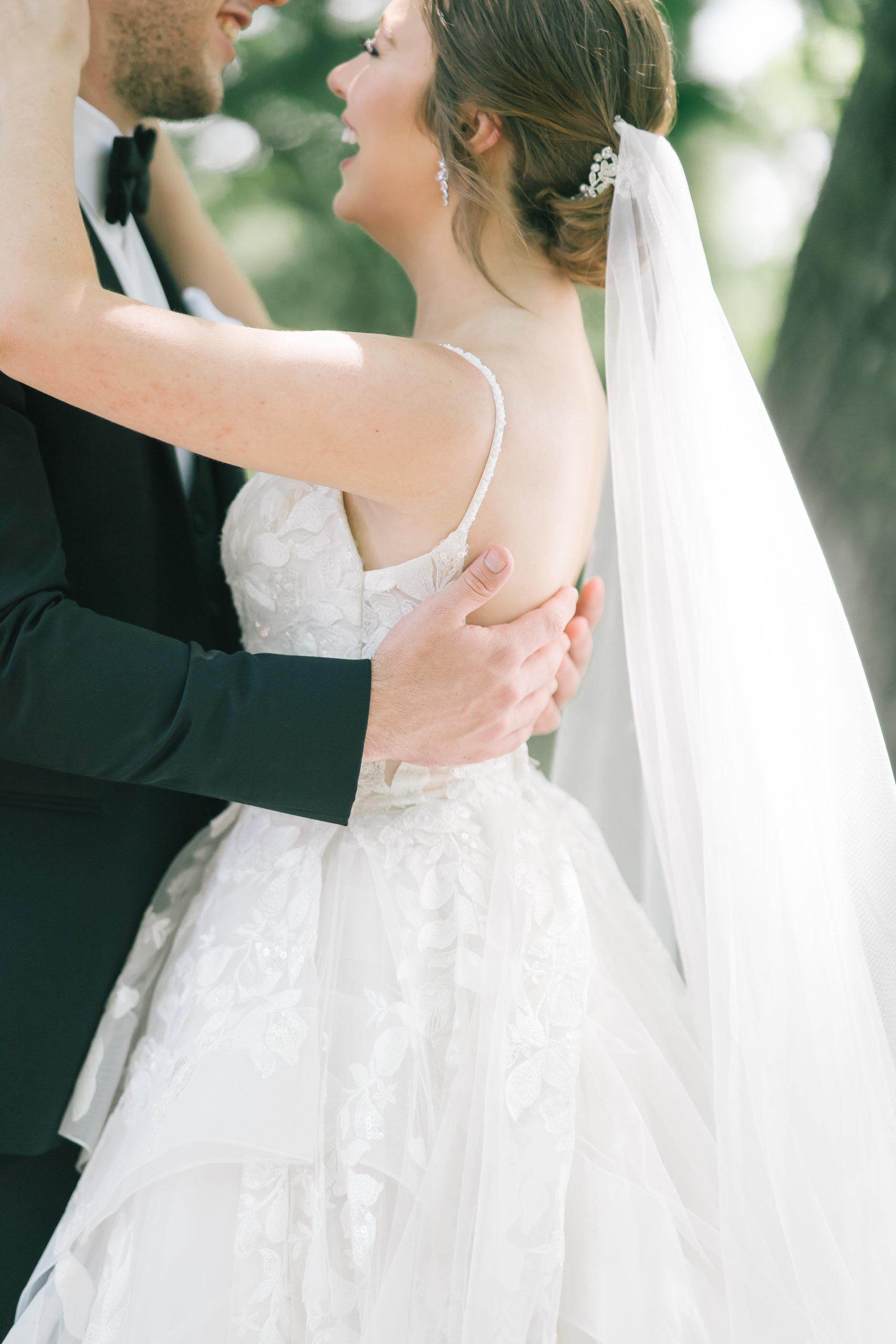 detail shot of groom holding his bride with a close up on the brides gown that is lined with tulle and lace for a classic summer wedding dress