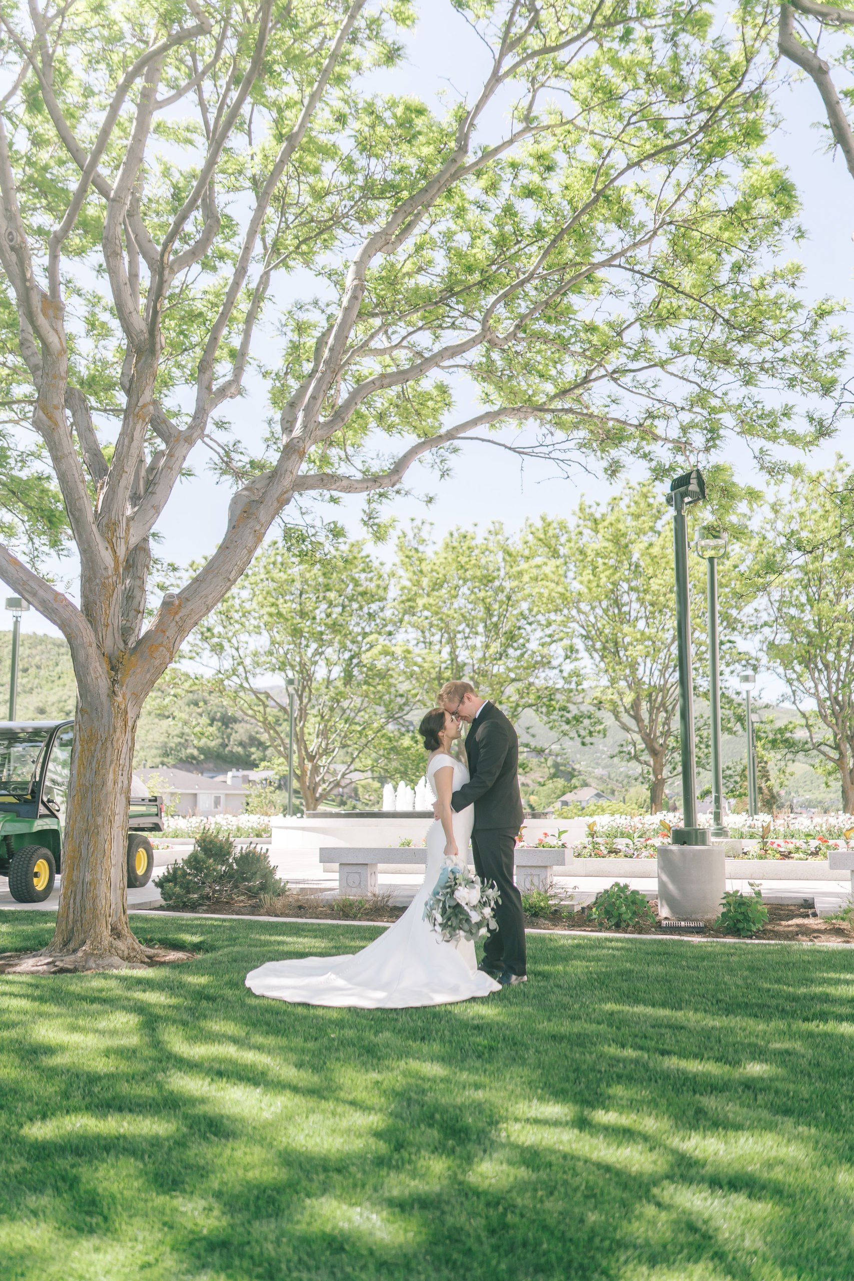simple satin wedding dresses in trend with bride and groom kissing each other in a green garden for their destination wedding captured by best Knoxville wedding photographer