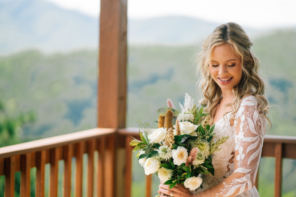 bride on the covered patio at the Magnolia in Pigeon Forge as she holds her wedding bouquet and smiles over her shoulder 
